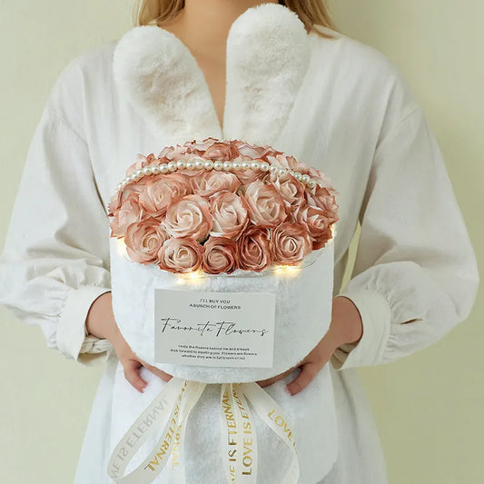Bunny Ear Rose Bouquet Person holding a bouquet of pink roses in a box with lights and a decorative ribbon.