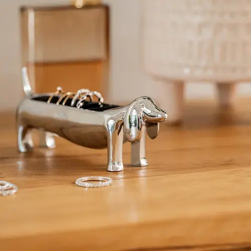 Dachsie Dog Ring Holder GiftDealAU product image. Silver dog-shaped ring holder on a wooden surface with rings around it.