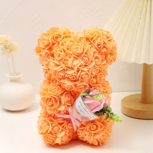Foam Rose Teddy Bear Holding Bouquet Orange teddy bear made of roses with a small bouquet on a white surface.
