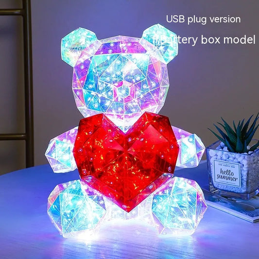 Holographic LED Teddy Bear Colorful geometric teddy bear lamp with a heart on a table.