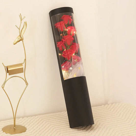 LED Flower Bouquet Gift Box Black cylindrical container with red roses and lights next to a gold deer figurine on a textured surface.