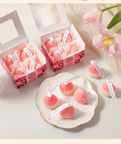 Strawberry Shaped Scented Candles box giftdealau product image. Pink strawberry-shaped candles in decorative boxes on a white surface with tulips.