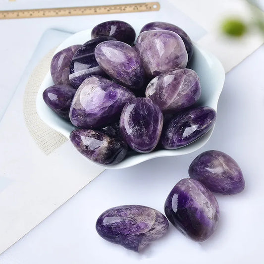 Amethyst Tumble Stone Purple stones in a white bowl with a ruler for scale on a light background