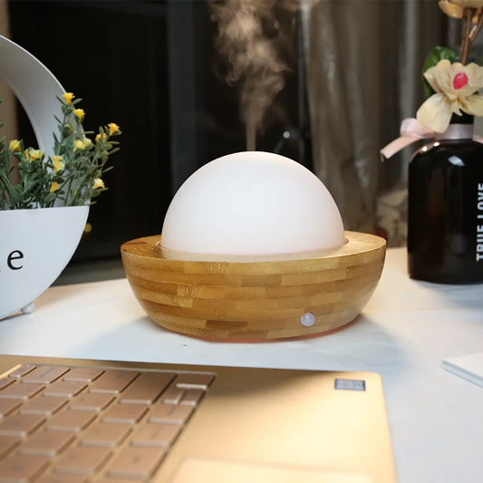 Aroma Natural Bamboo Diffuser Wooden diffuser emitting steam on a desk with a laptop and decorative items.