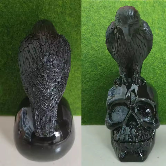 Black Obsidian Raven on Skull Carving Black bird figurine perched on a skull against a green background