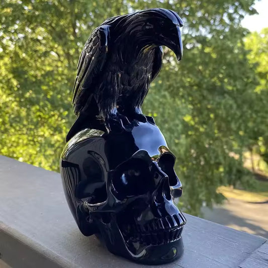 Black Obsidian Raven on Skull Carving Black raven perched on a black skull with a blurred green outdoor background