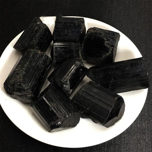 Black Tourmaline Raw Chunk Black stone blocks on a white plate against a black background
