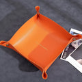 Suede Valet Tray Leather Catchall Tray Orange leather tray on a dark surface with magazines underneath
