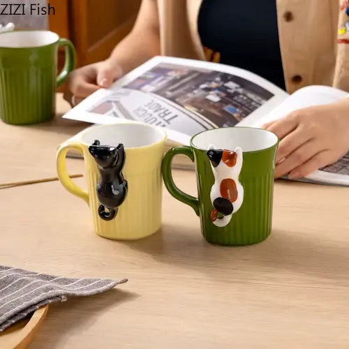Cute 3D Cat Hanging Mug green and beige variant GiftDealAU product image. Two mugs with animal handles on a table, one person reading a newspaper in the background.