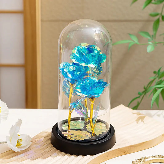 Galaxy Enchanted Rose Dome Blue roses under a glass dome on a decorative stand with a blurred background
