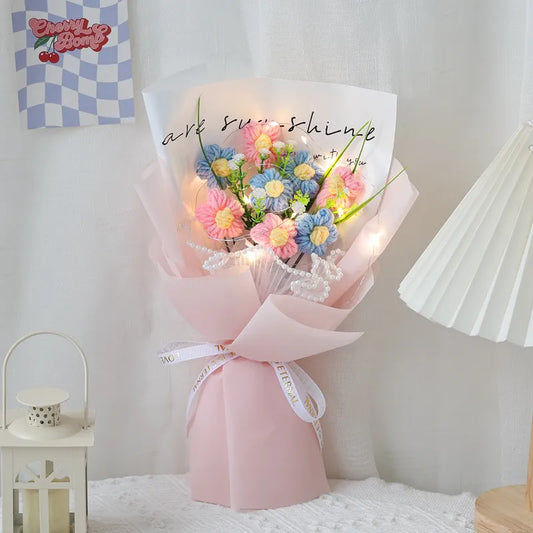 Handmade Crochet Flower Bouquet of flowers wrapped in pink paper with LED lights on a bed.
