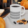 Hidden Message Ceramic Coffee Mug GiftDealAU Ptoduct image. White mug with black patterns on a table with Halloween-themed treats and pumpkins.