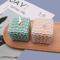 Honeycomb Cube Candle
green and pink blowing candle variant GiftDealAU product image. Two honeycomb-patterned candles on a wooden board with a magazine in the background.