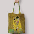 Klimt The Kiss Tote Bag front side GiftDealAU product image. Tote bag with 'The Kiss' by Gustav Klimt design held by a hand on a light gray background