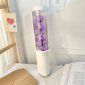 LED Flower Bouquet Gift Box White cylindrical vase with purple roses on a textured surface with a light background