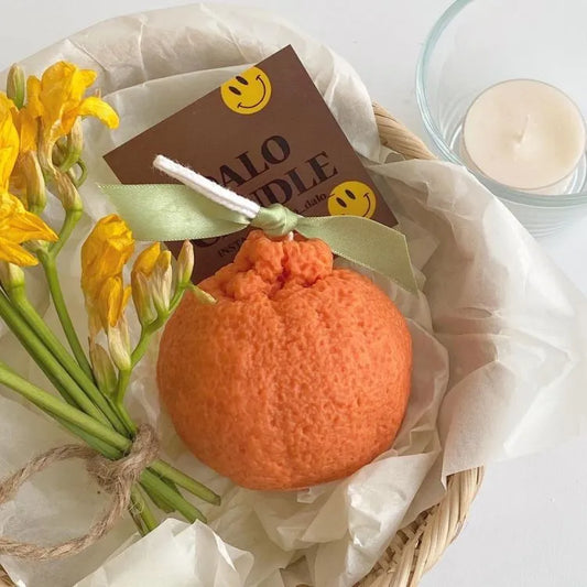 Pumpkin Shaped Soy Candles Orange candle with yellow flowers and a smiley face card on a white background