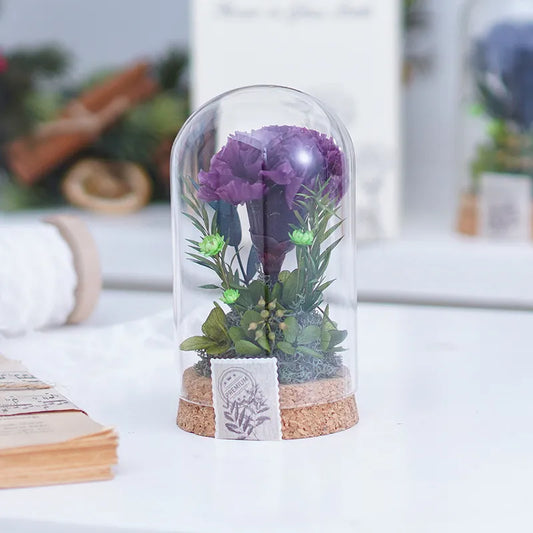 Preserved Flower in Glass Dome Purple flower in a glass dome on a white surface with a blurred background