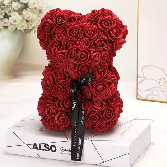 Red rose teddy bear with a black ribbon on a white surface