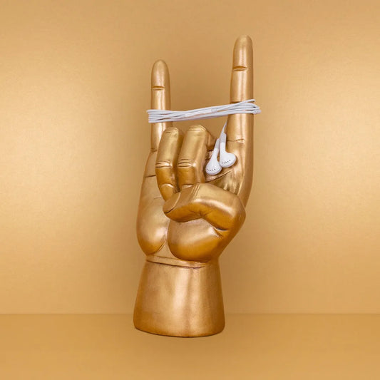 Rock On Statue Ring Holder Gold hand sculpture making a rock sign with earphones on a beige background