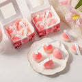 Strawberry Shaped Scented Candles
giftdealau product image. Strawberry-shaped candles with small white labels on a light surface, surrounded by pink tulips.