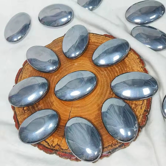 Terahertz Palm Stone Silver oval stones on a wooden coaster with additional stones around.