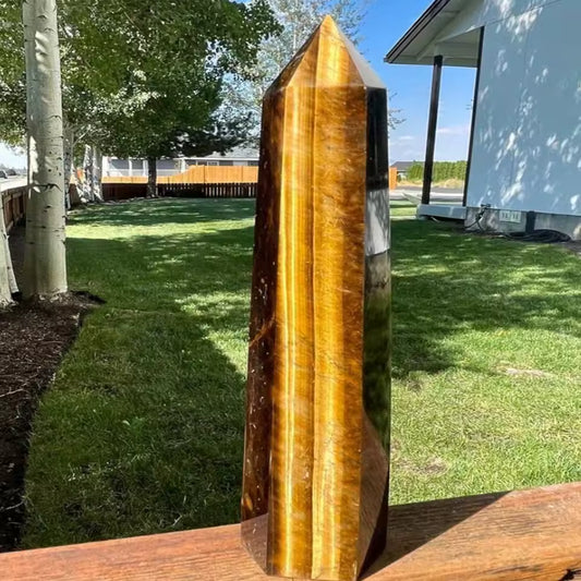 Tiger's eye crystal on a wooden surface with a grassy area and trees in the background
